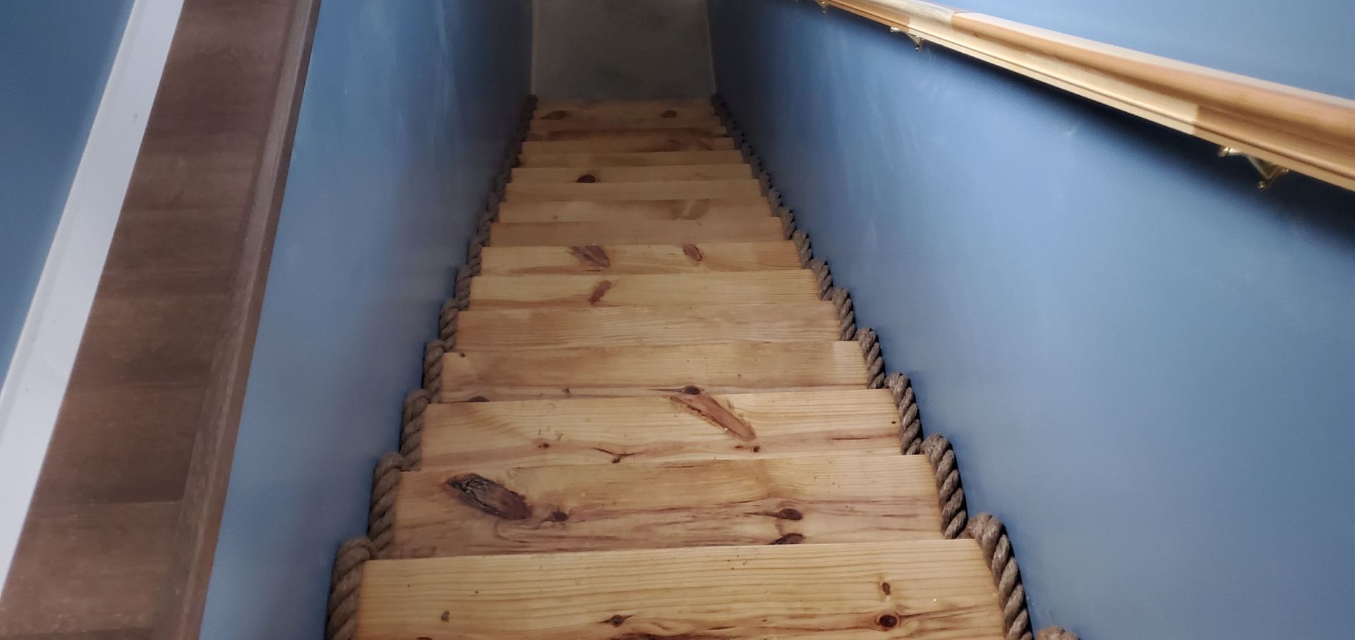 A wooden staircase leading up to a blue wall.