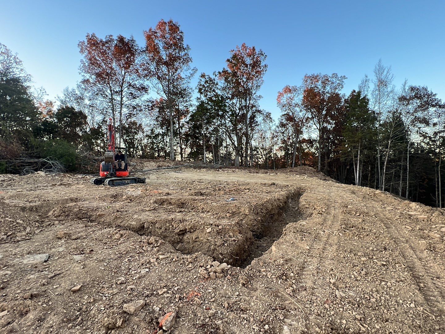 A dirt road with trees in the background and a bulldozer in the foreground