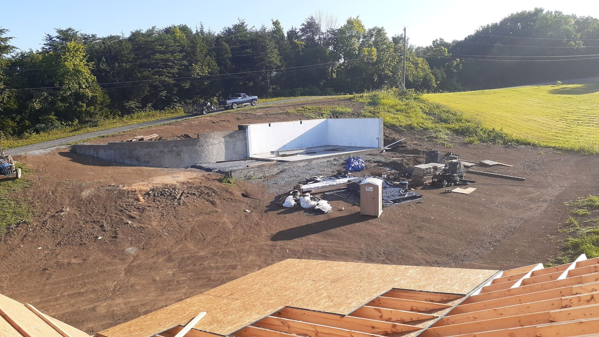 A large white building is being built in the middle of a dirt field.
