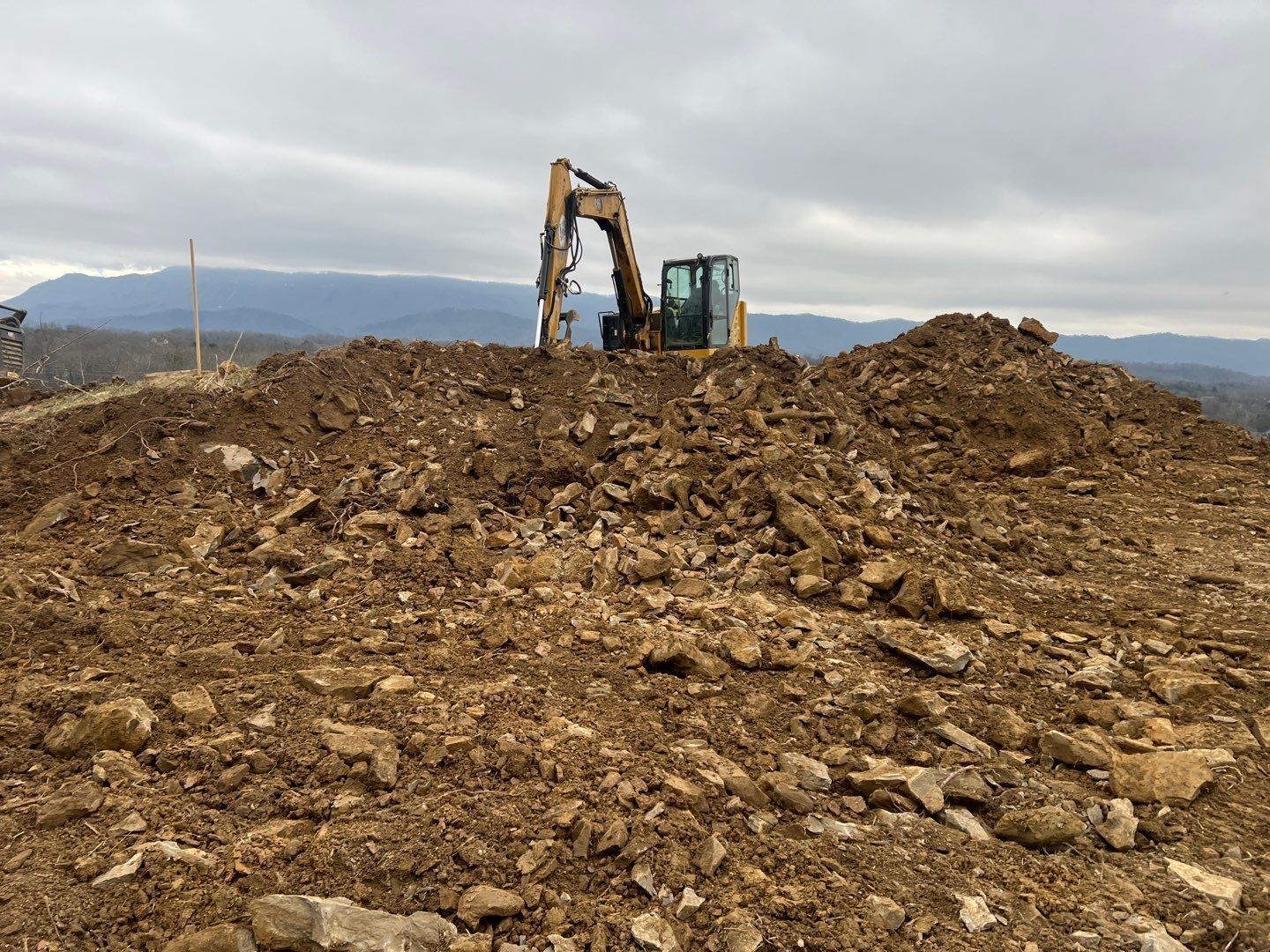 A bulldozer is sitting on top of a pile of dirt and rocks.
