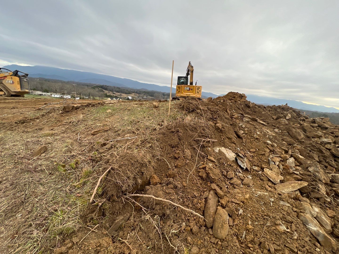 A bulldozer is working on a pile of dirt in a field.