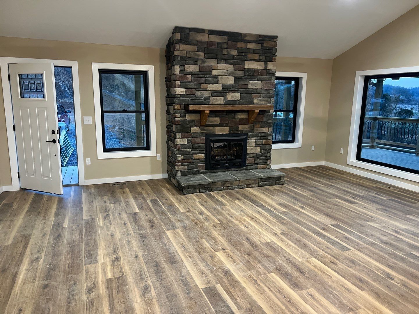 A living room with hardwood floors and a stone fireplace.
