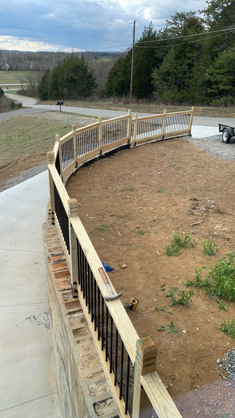 A wooden fence is sitting on top of a dirt hill next to a road.