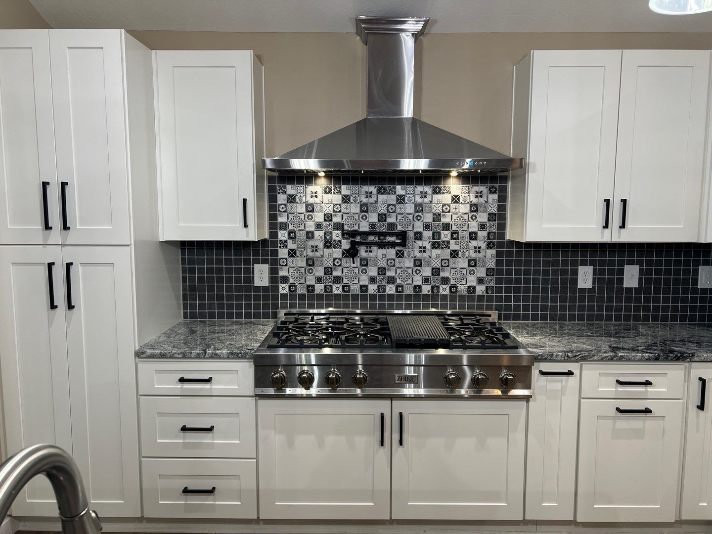 A kitchen with white cabinets and a stove top oven.