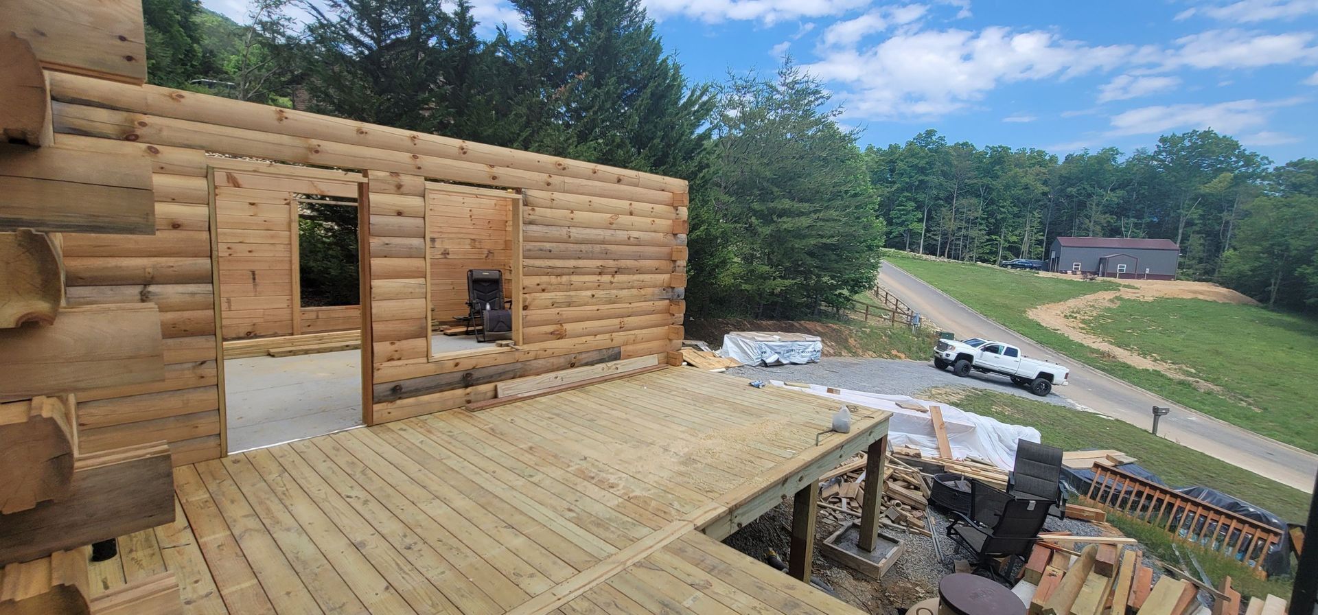 A log cabin is being built on top of a wooden deck.