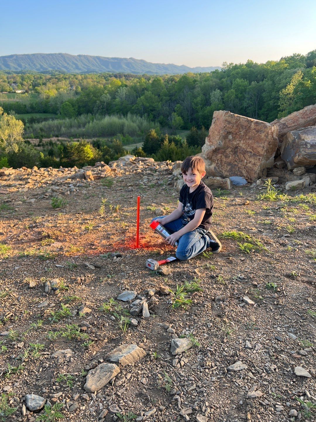 A young boy is sitting on the ground playing with a toy rocket.