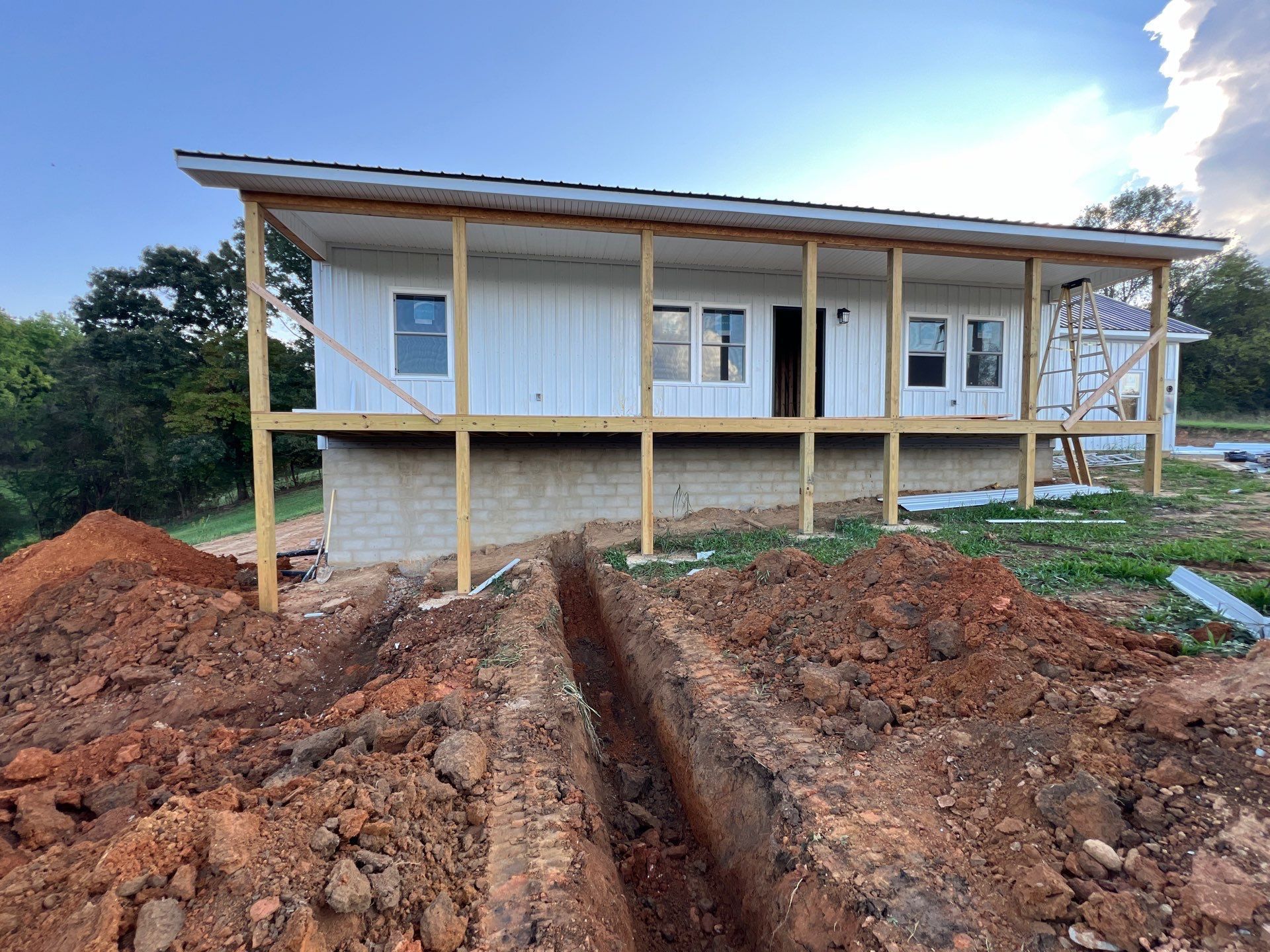 A white house is being built on top of a dirt hill.
