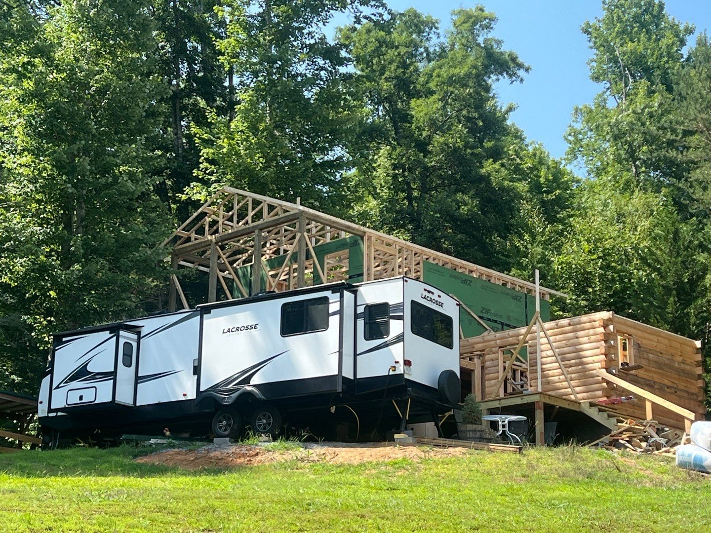 Two rvs are parked in front of a house under construction.