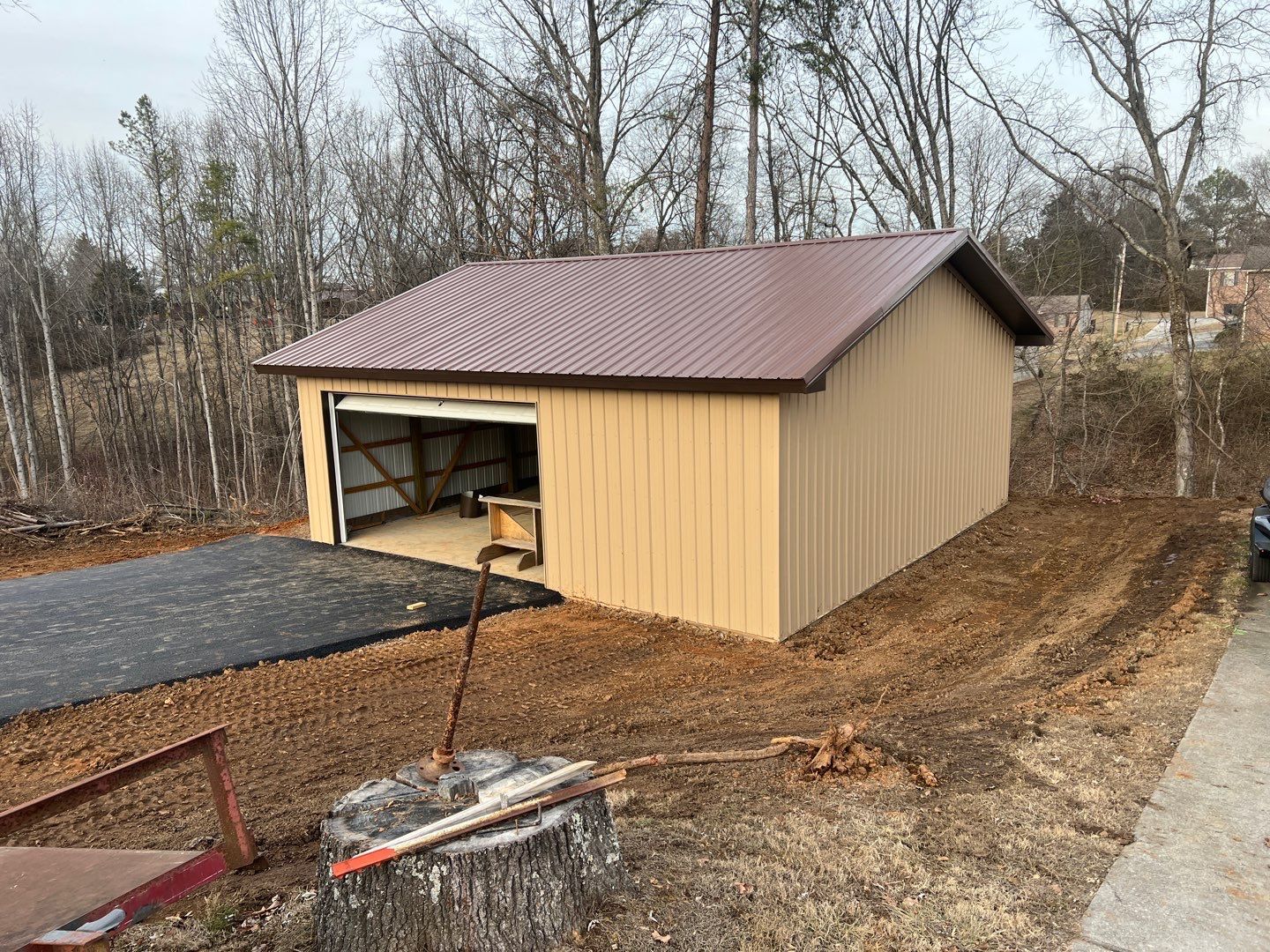 A garage with a brown roof is sitting in the middle of a dirt field.