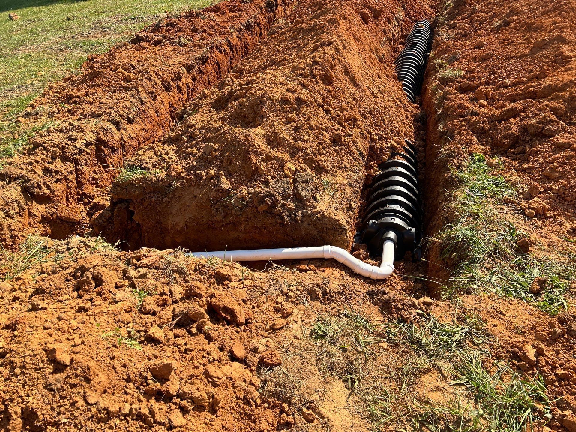 A pipe is being installed in the dirt in a field.