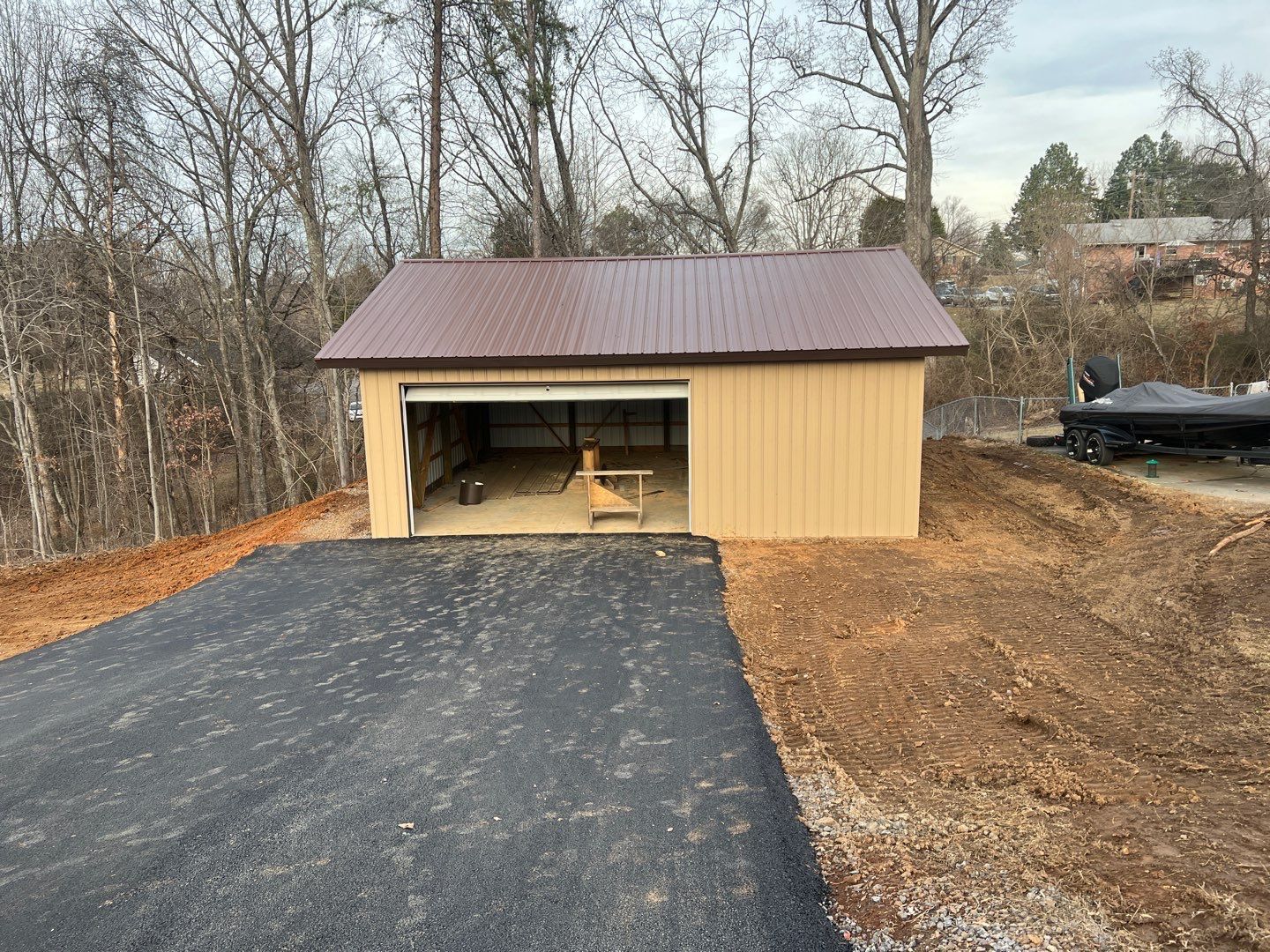 A garage with a brown roof and a boat in the background.