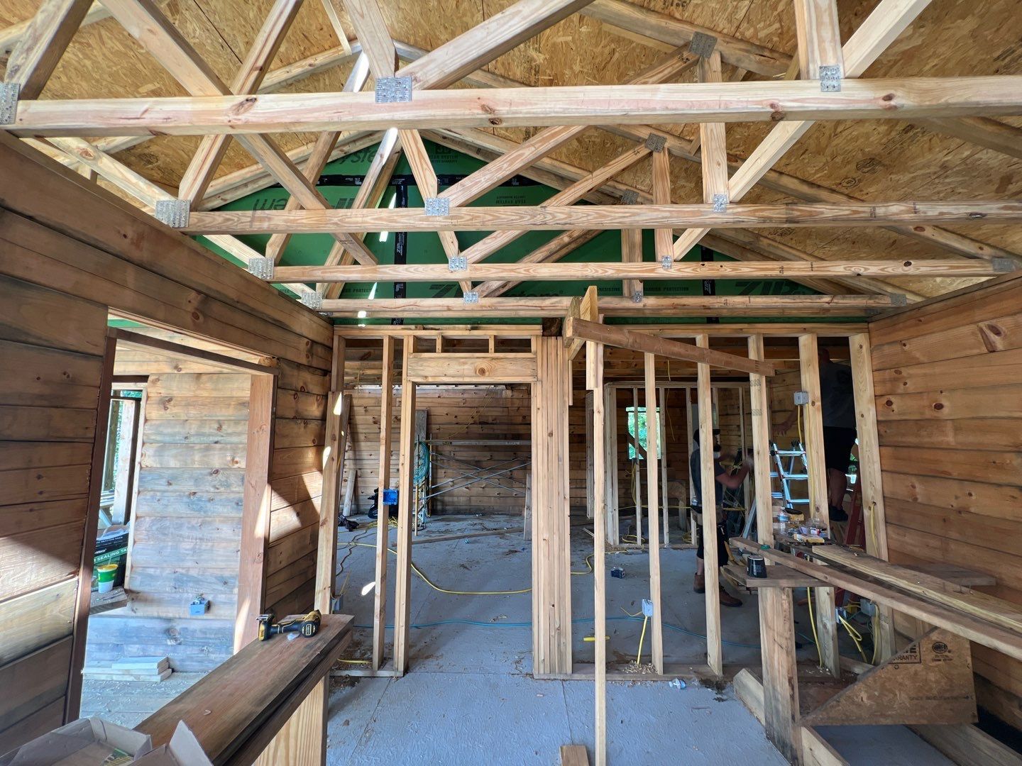 The inside of a wooden house under construction with a green roof.