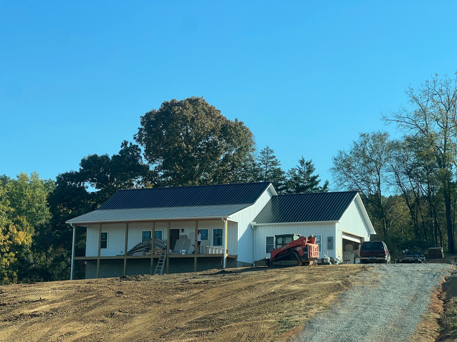 A white house with solar panels on the roof is sitting on top of a dirt hill.