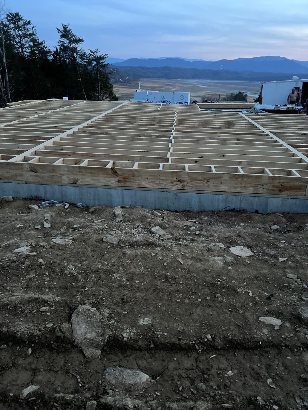 A wooden floor is being built in a field with mountains in the background