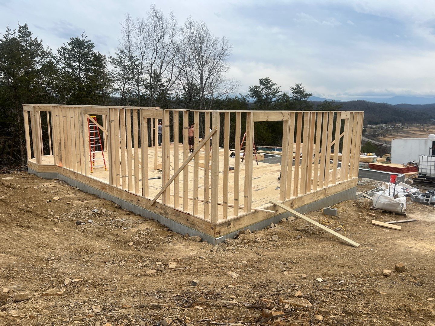 A wooden house is being built on top of a dirt hill.