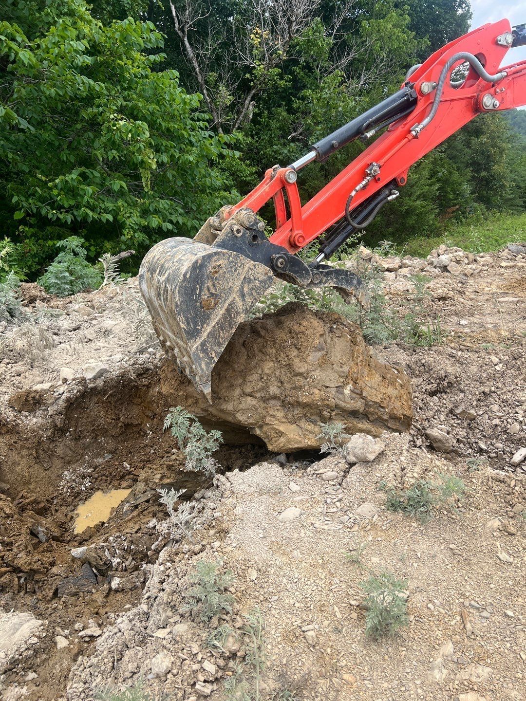 A red excavator is digging a hole in the ground