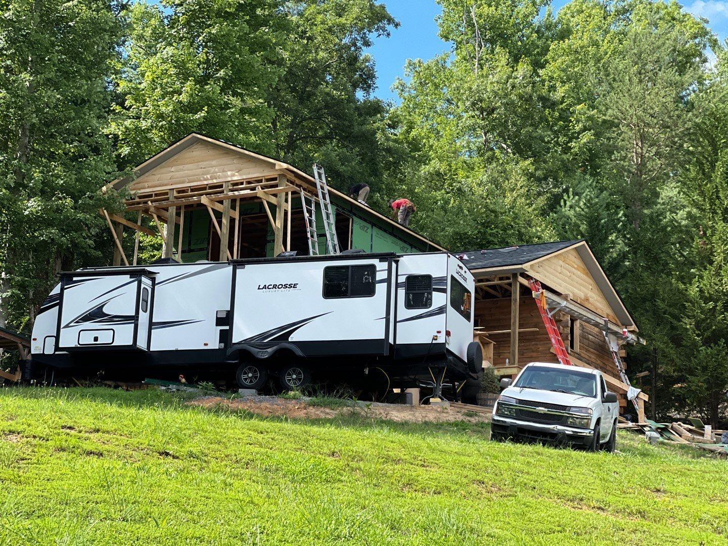 A rv is parked in front of a house under construction.