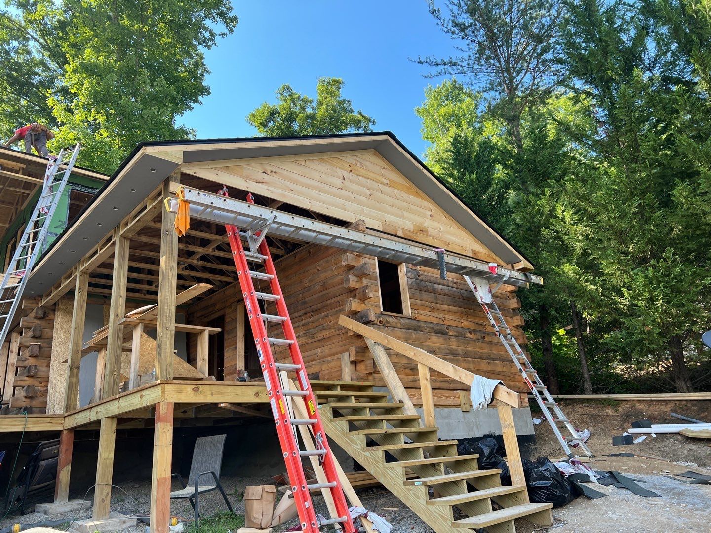 A wooden cabin is being built with stairs and a ladder.