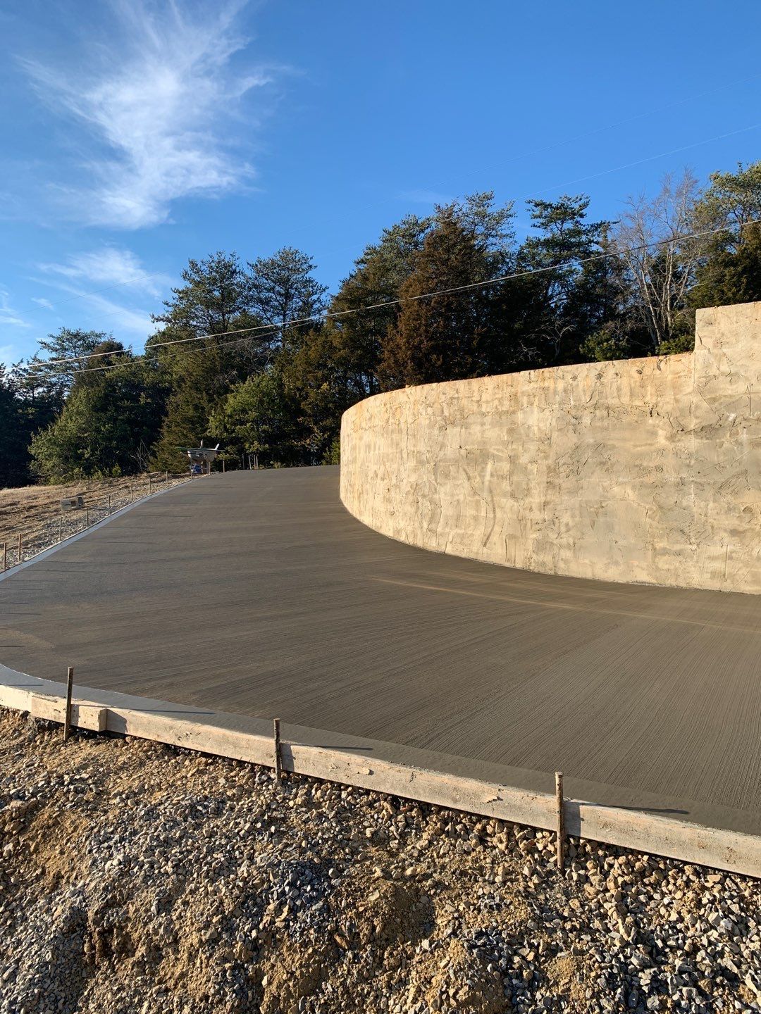 A concrete driveway is being built next to a stone wall.