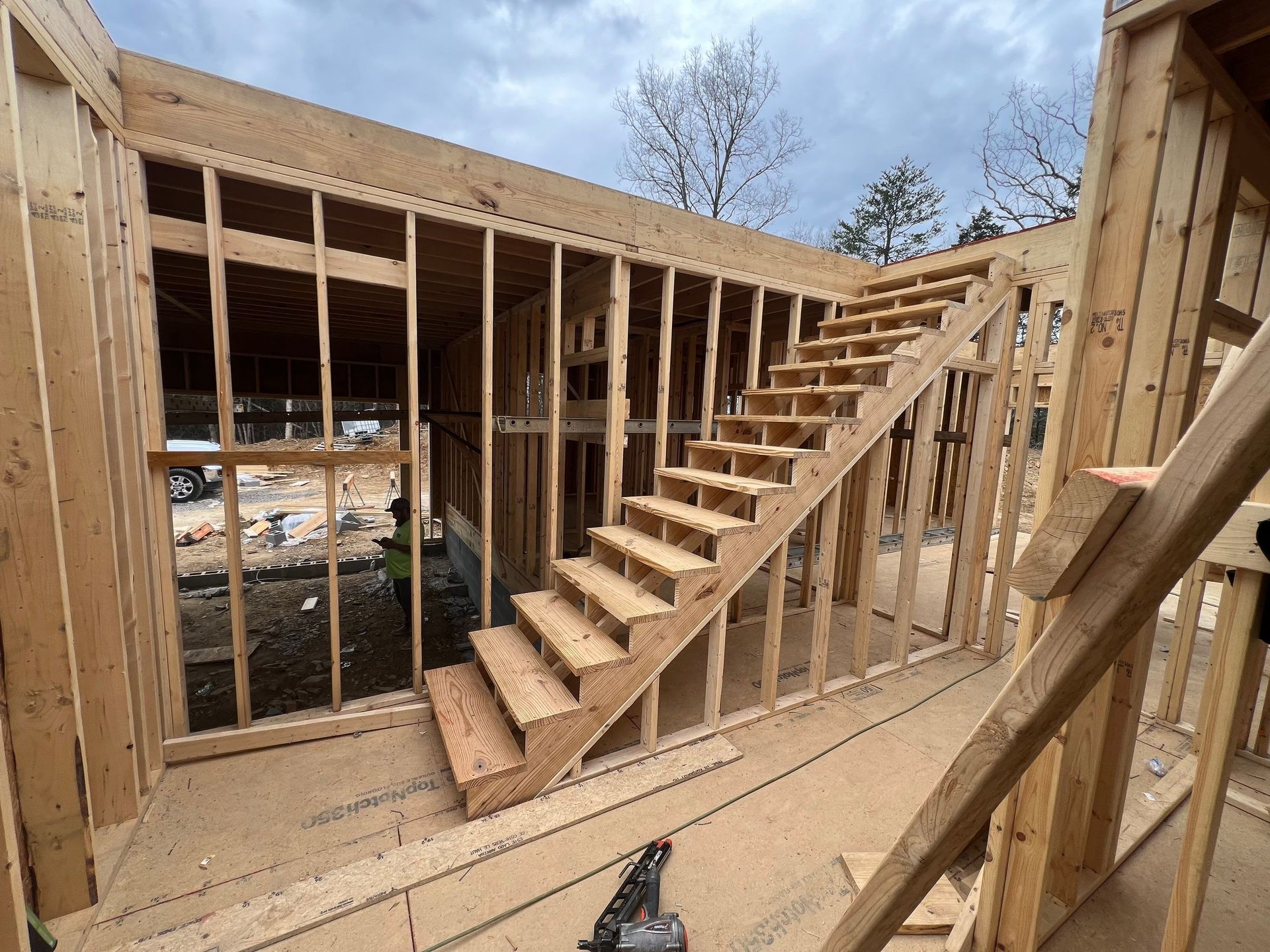 A wooden staircase is being built in a house under construction.