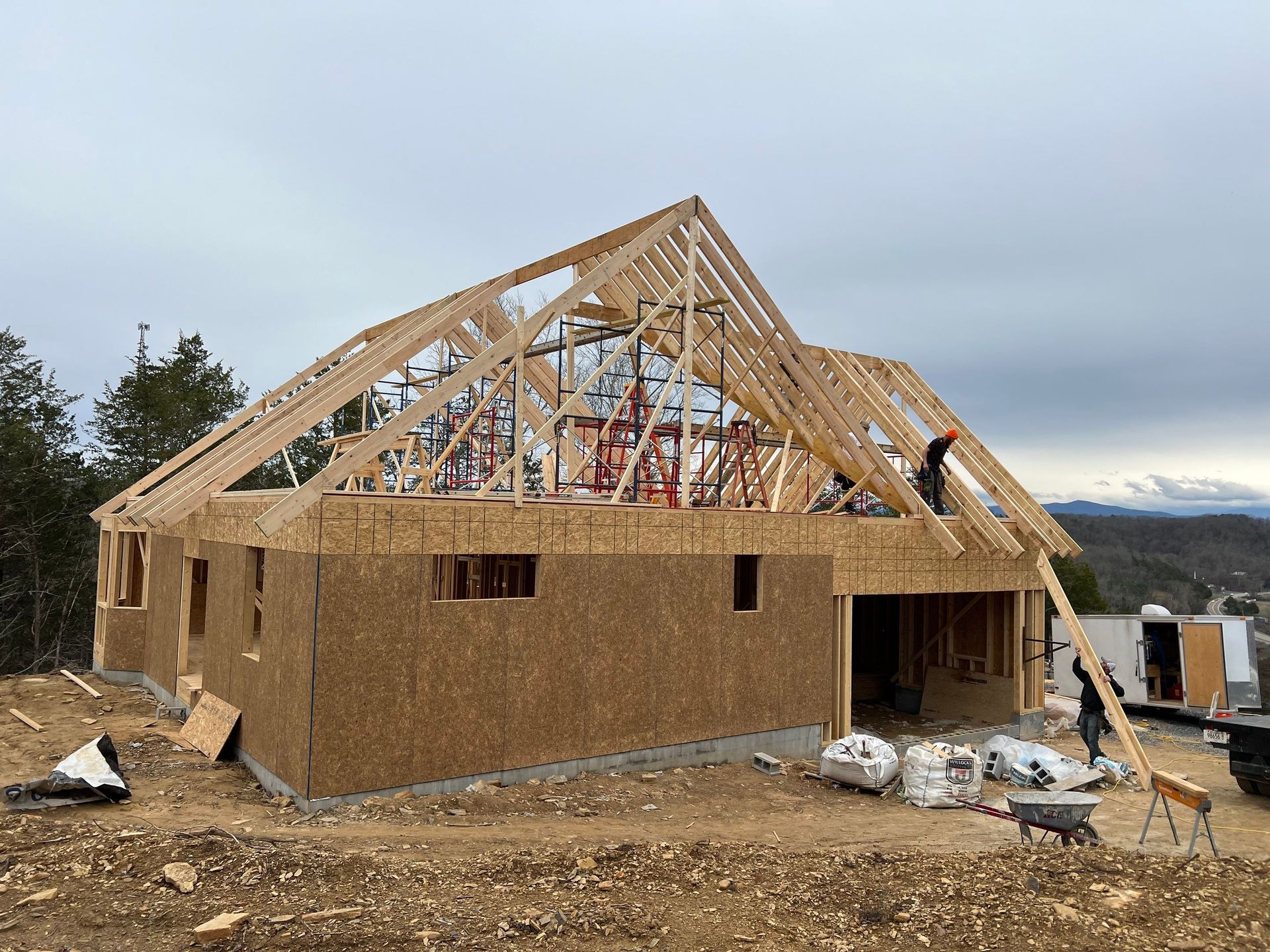 A large wooden house is being built on top of a dirt hill.