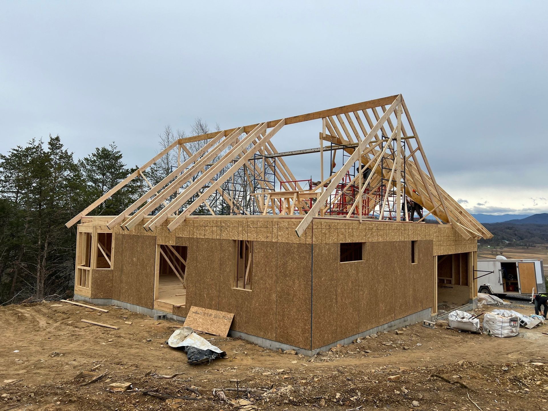 A wooden house is being built on top of a dirt hill.