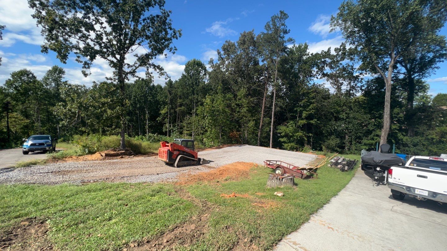 A red bulldozer is parked on the side of the road next to a white truck.