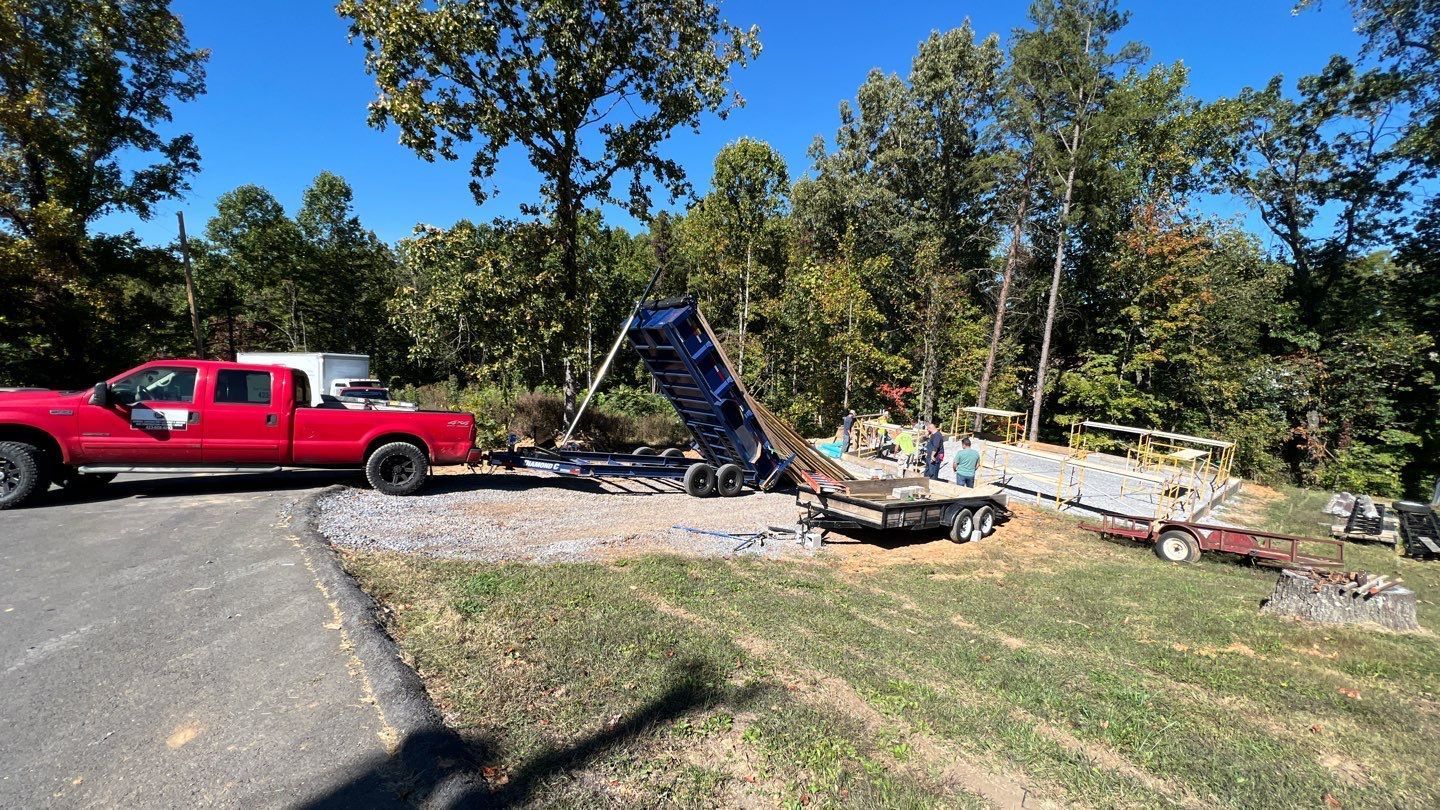 A red truck is parked on the side of the road next to a trailer.
