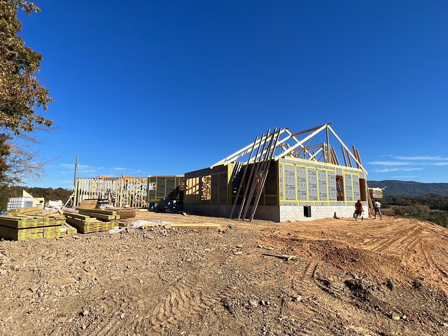A large house is being built on top of a dirt hill.