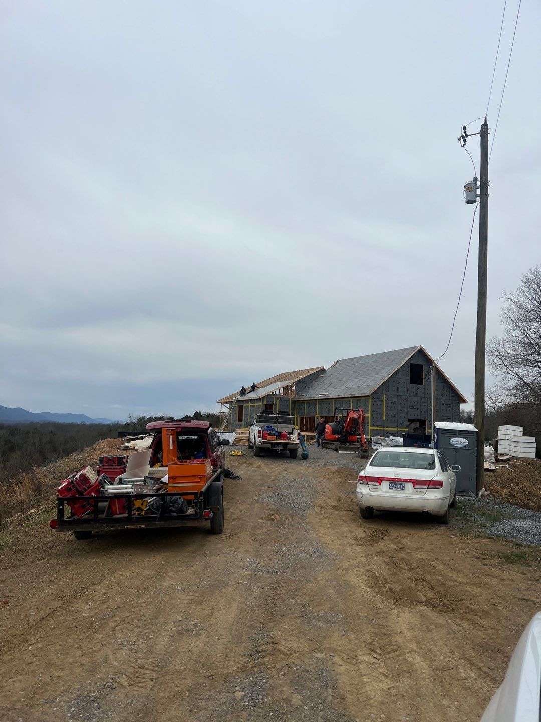 A white car is parked in front of a house under construction.