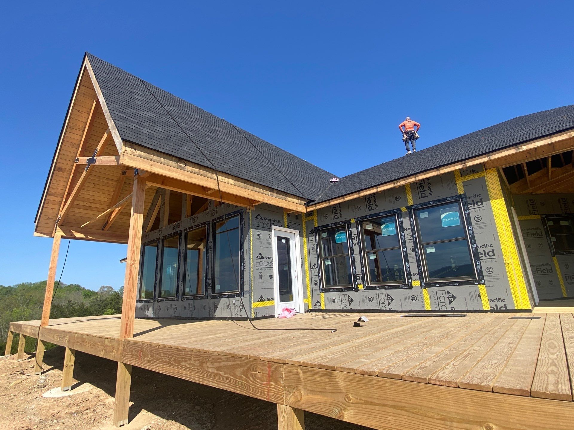 A man is standing on the roof of a house under construction.