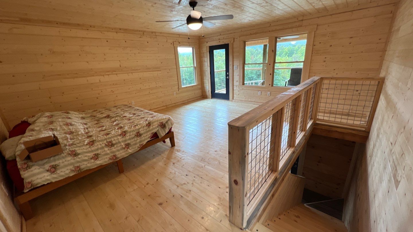 A bedroom with a bed , stairs and a ceiling fan.