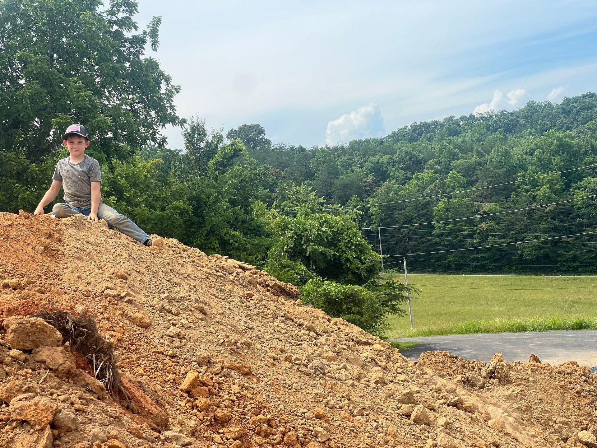 A young boy is sitting on top of a pile of dirt.