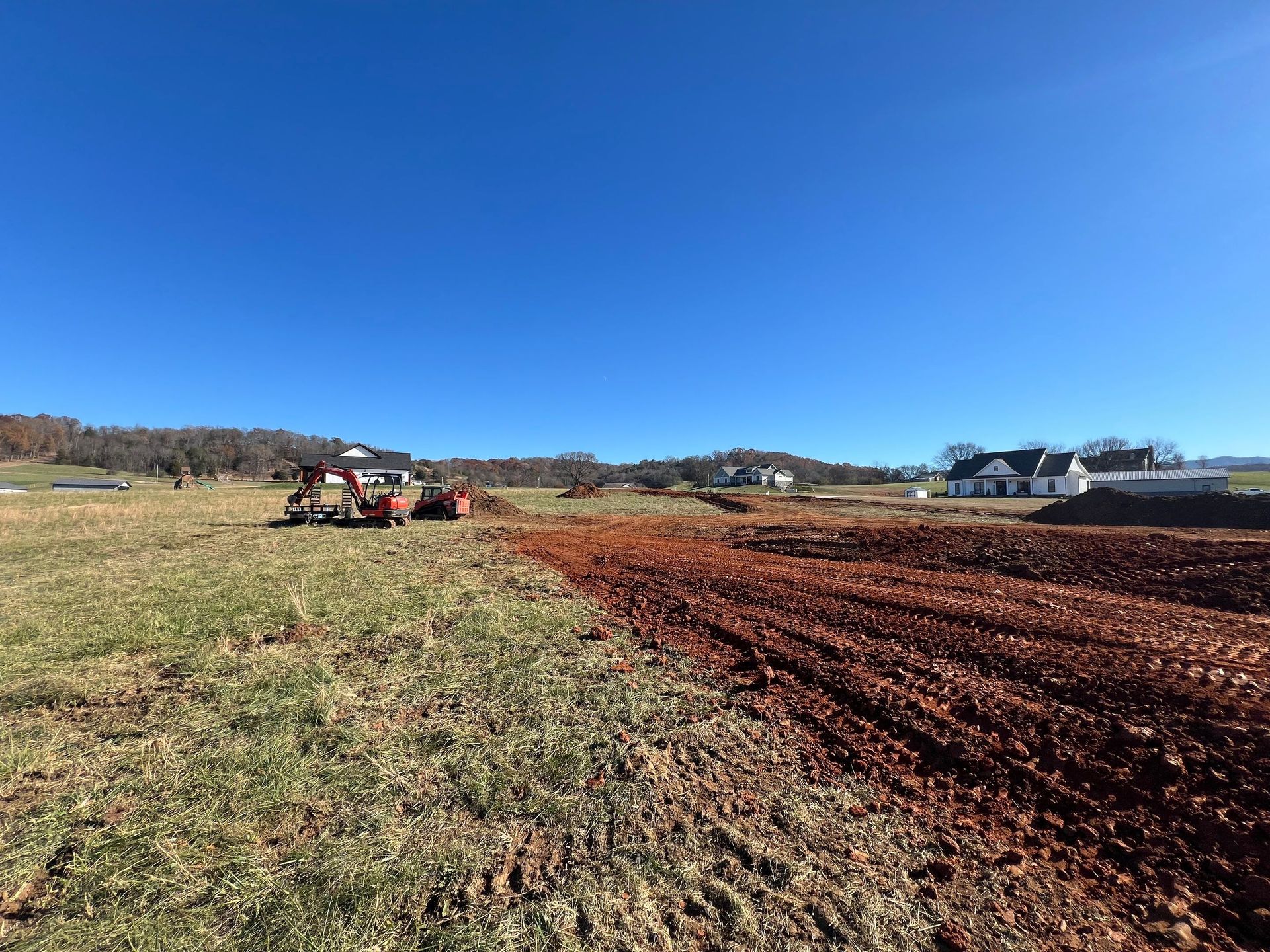 A tractor is driving down a dirt road in a field.