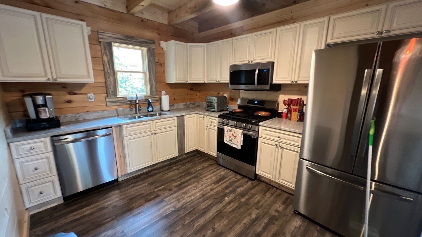 A kitchen in a log cabin with stainless steel appliances and white cabinets.