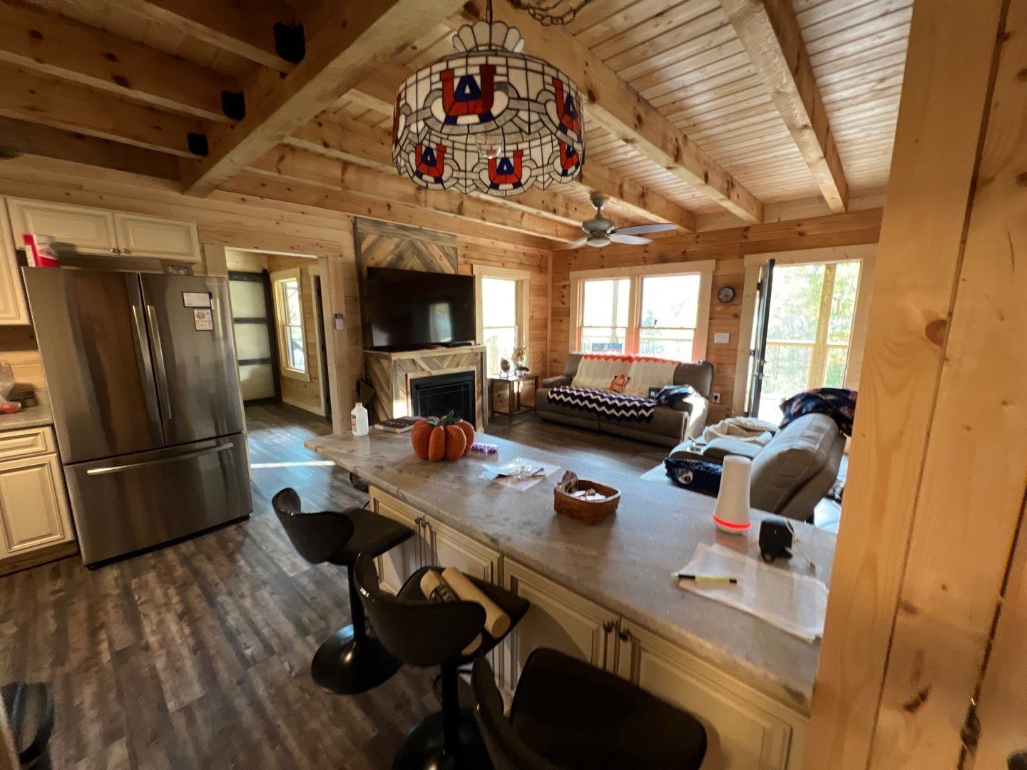A kitchen and living room in a log cabin with a chandelier hanging from the ceiling.