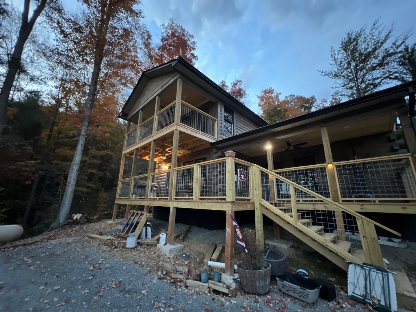 A house with a large deck and stairs is surrounded by trees.
