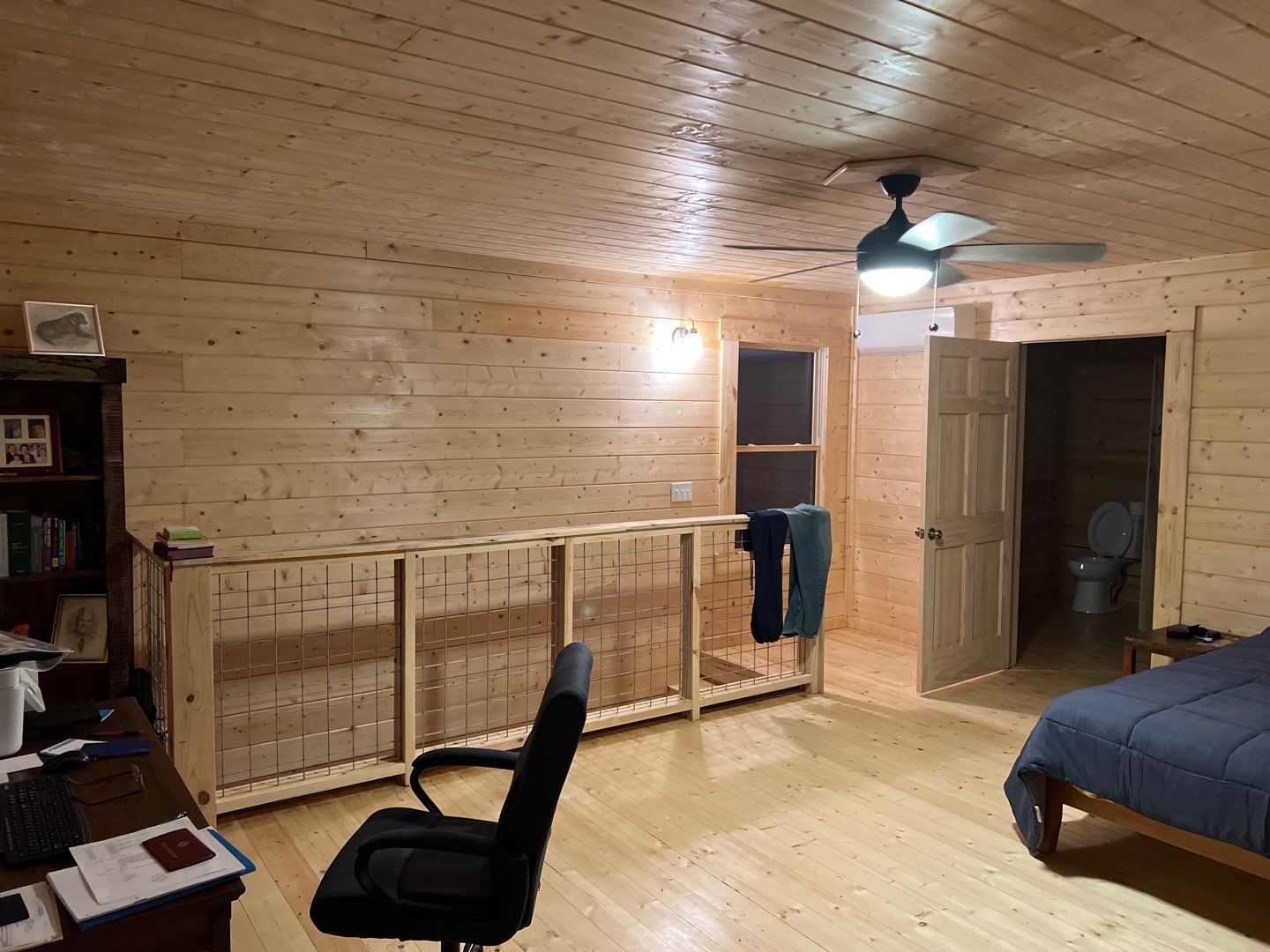 A bedroom with wood paneling and a ceiling fan