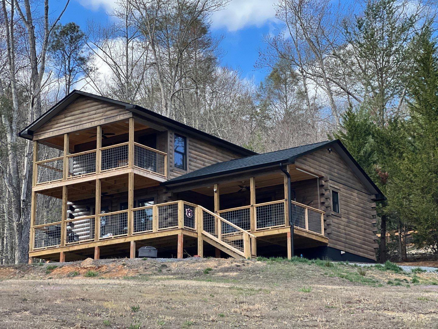 A large wooden house with a large deck in the middle of a field.