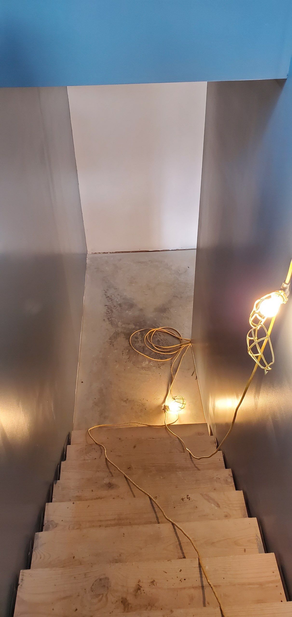 A wooden staircase leading up to a stainless steel wall.