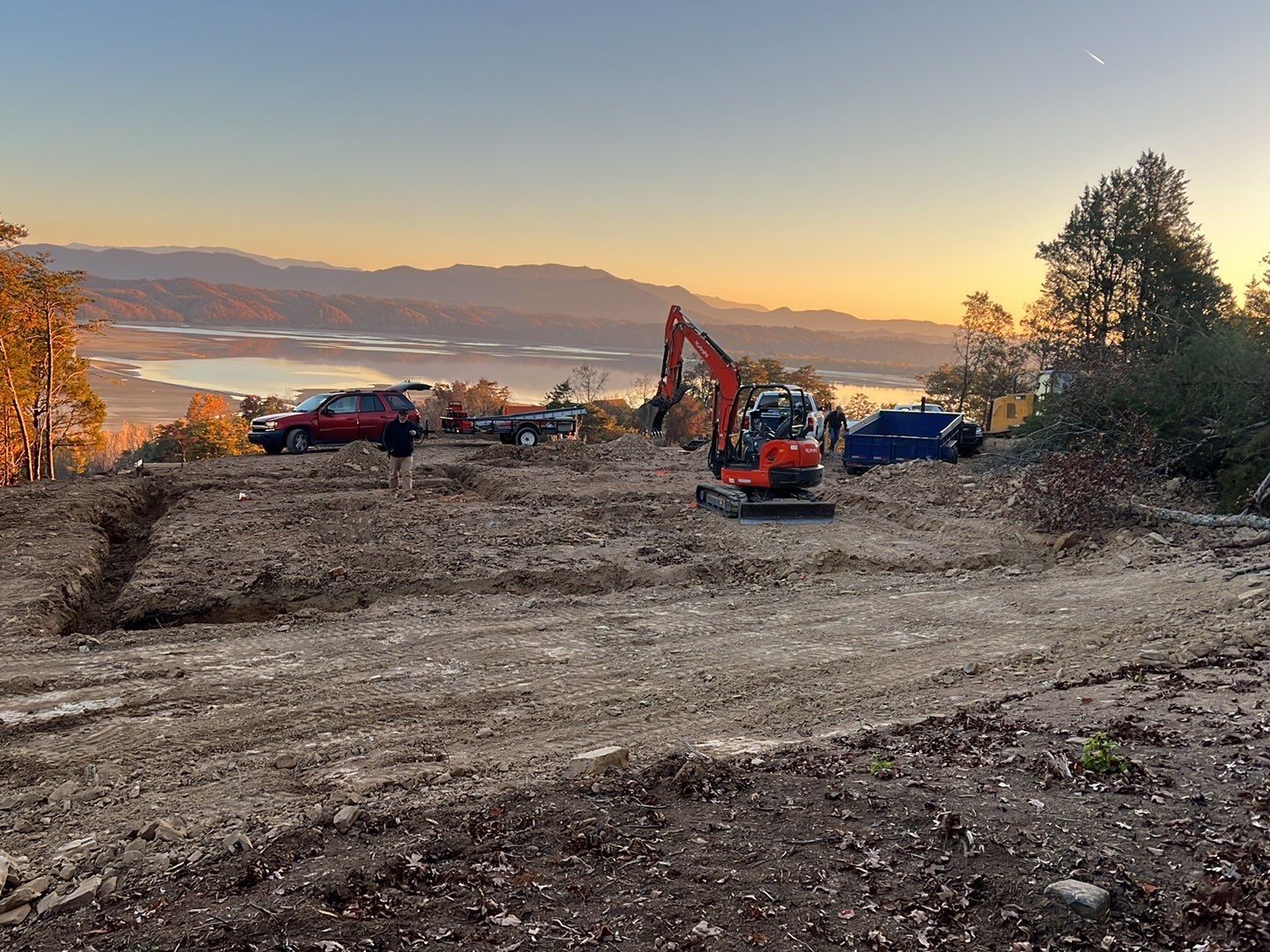 A large excavator is sitting in the middle of a dirt field.
