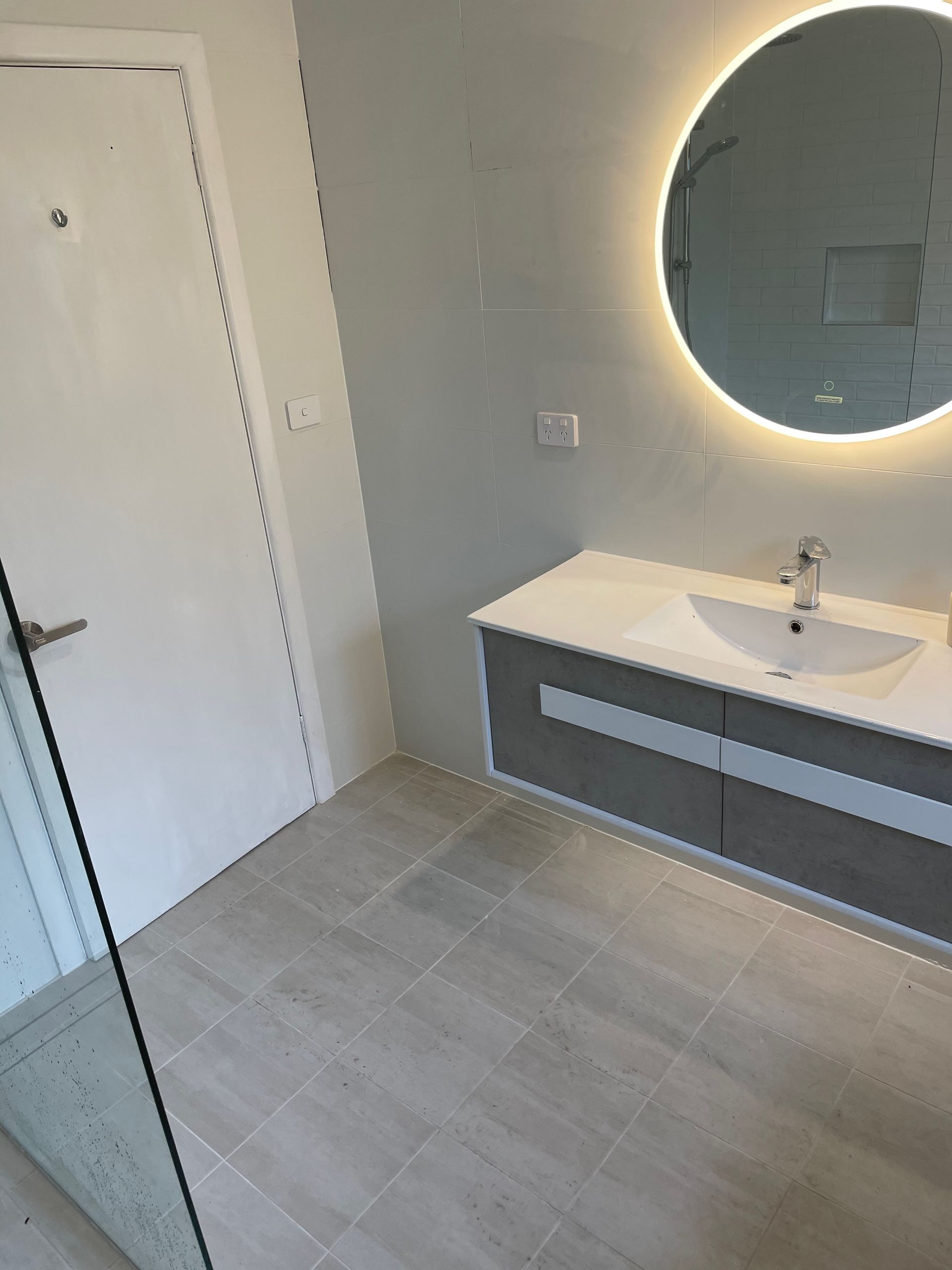 A bathroom with a sink and a round mirror.