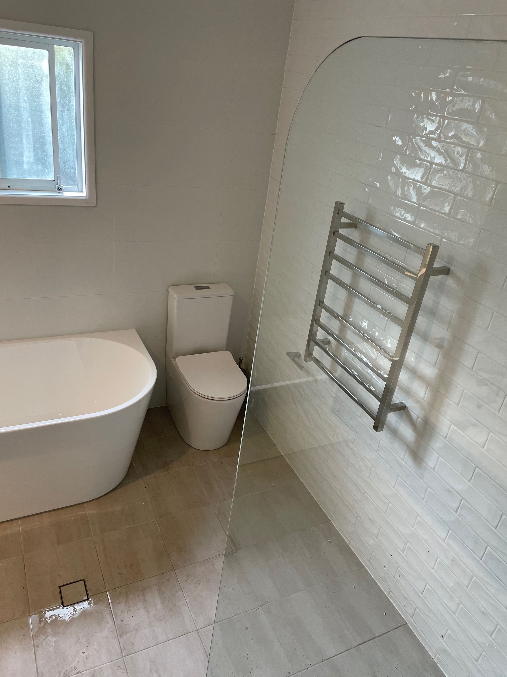 A bathroom with a bathtub , toilet , and towel rack.