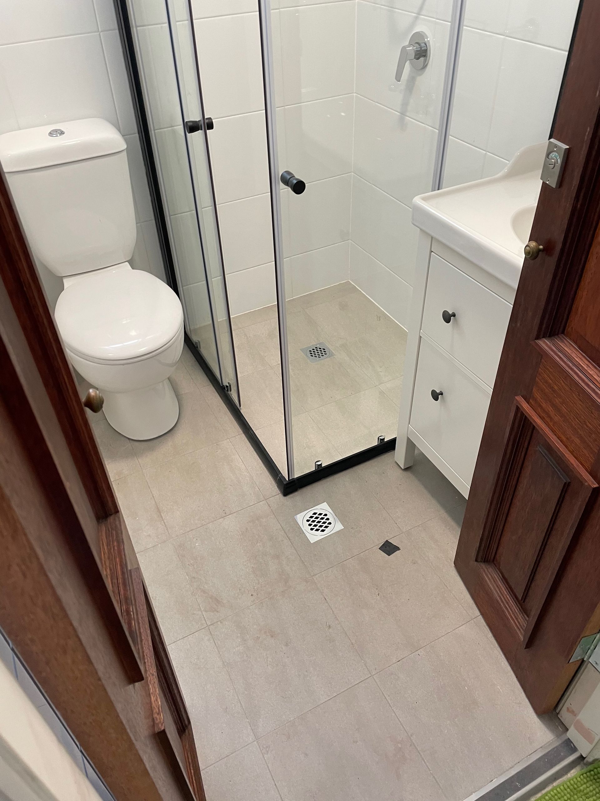 A bathroom with a toilet , sink and shower.