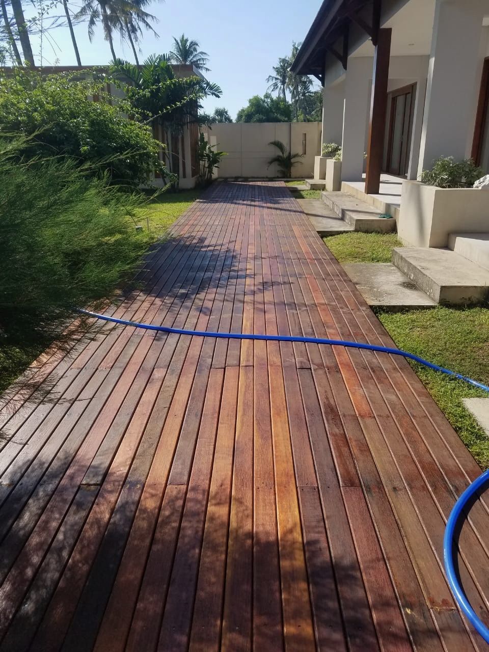 A wooden walkway with a blue hose on it