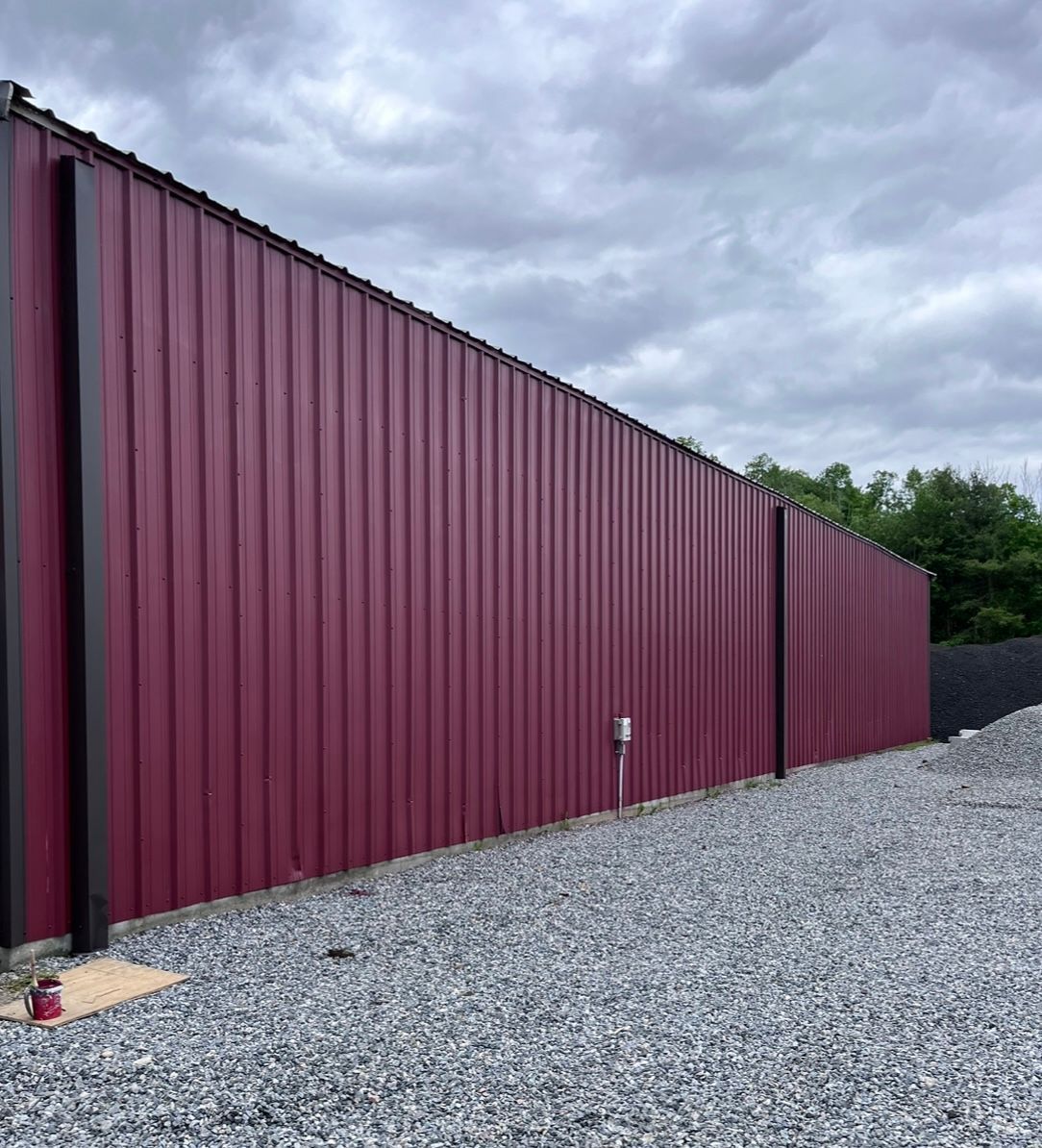 A large red metal fence is sitting on top of a gravel lot.