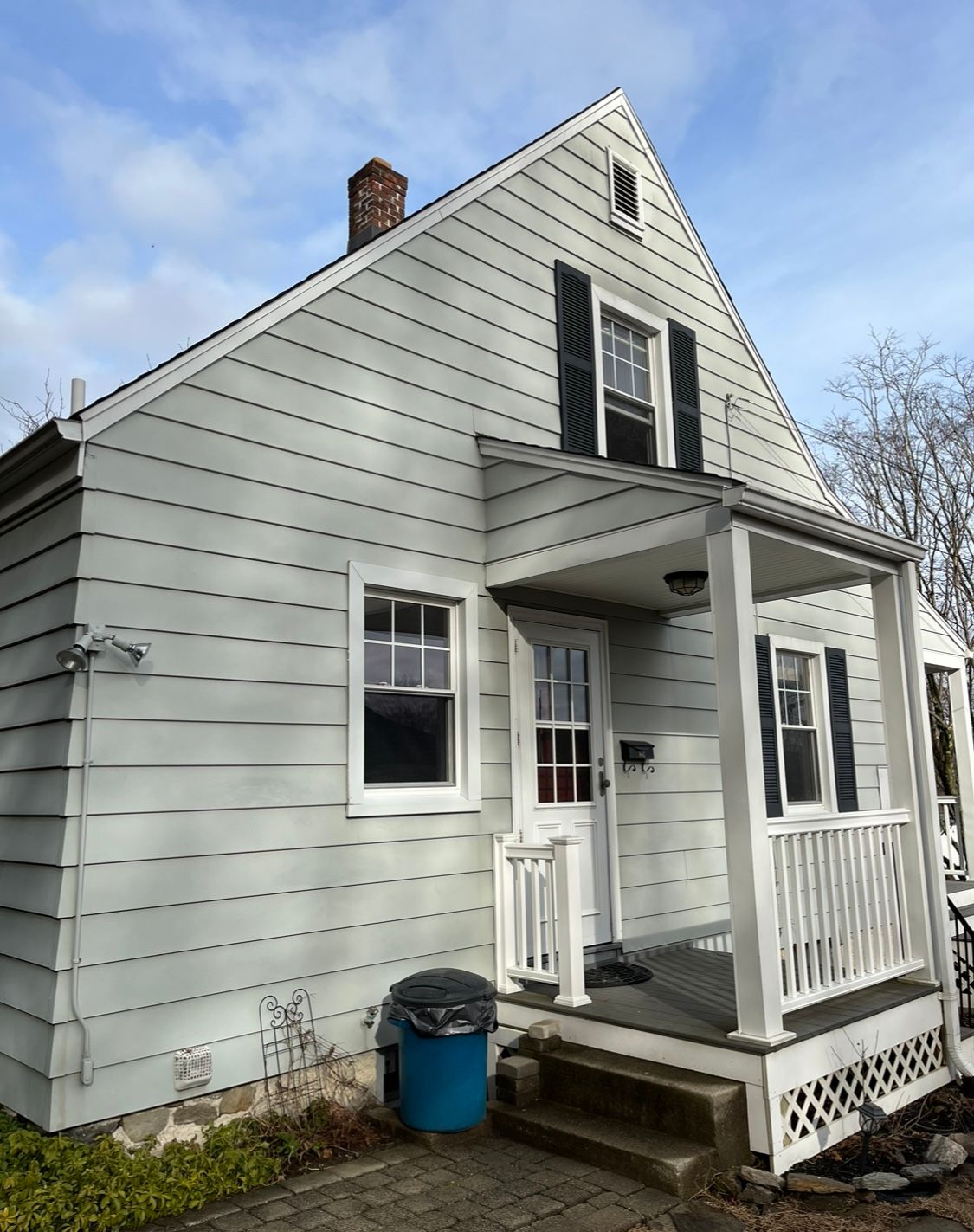 A white house with black shutters and a porch
