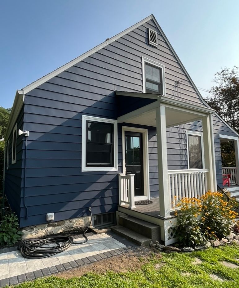 A blue house with a white porch and a blue sky in the background.