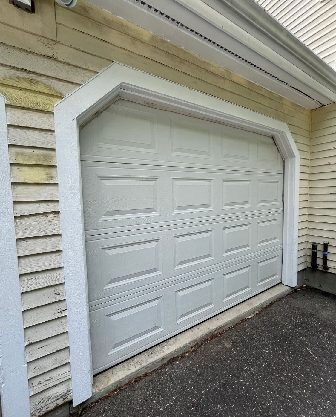 A white garage door is sitting on the side of a house.