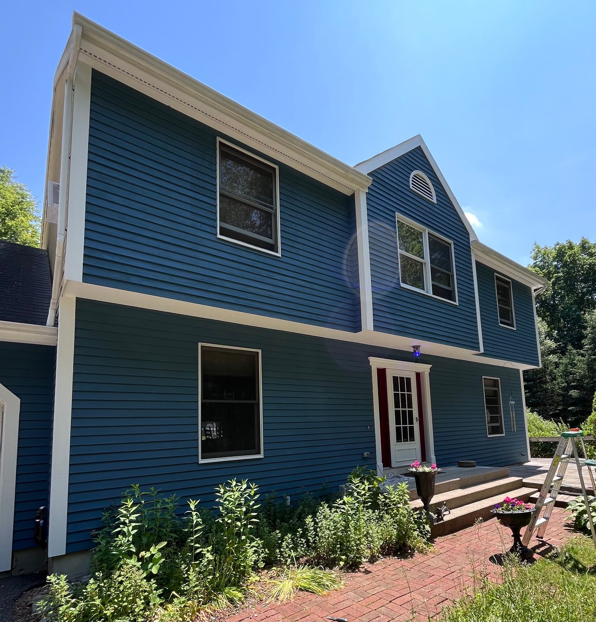 A blue and white house with a ladder in front of it.